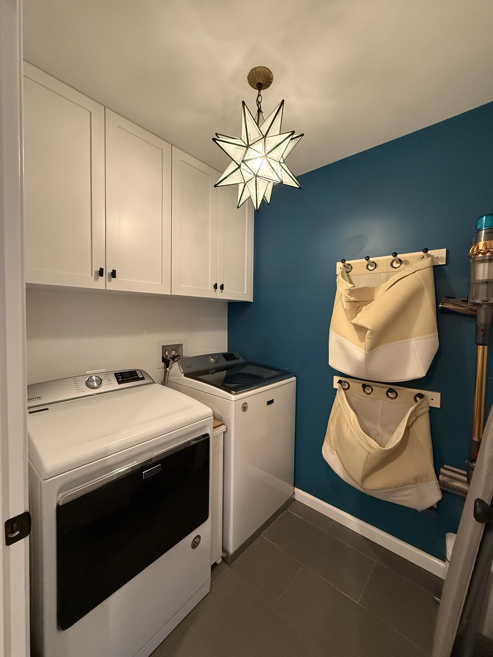 Relocated laundry room with cabinetry and blue accent wall