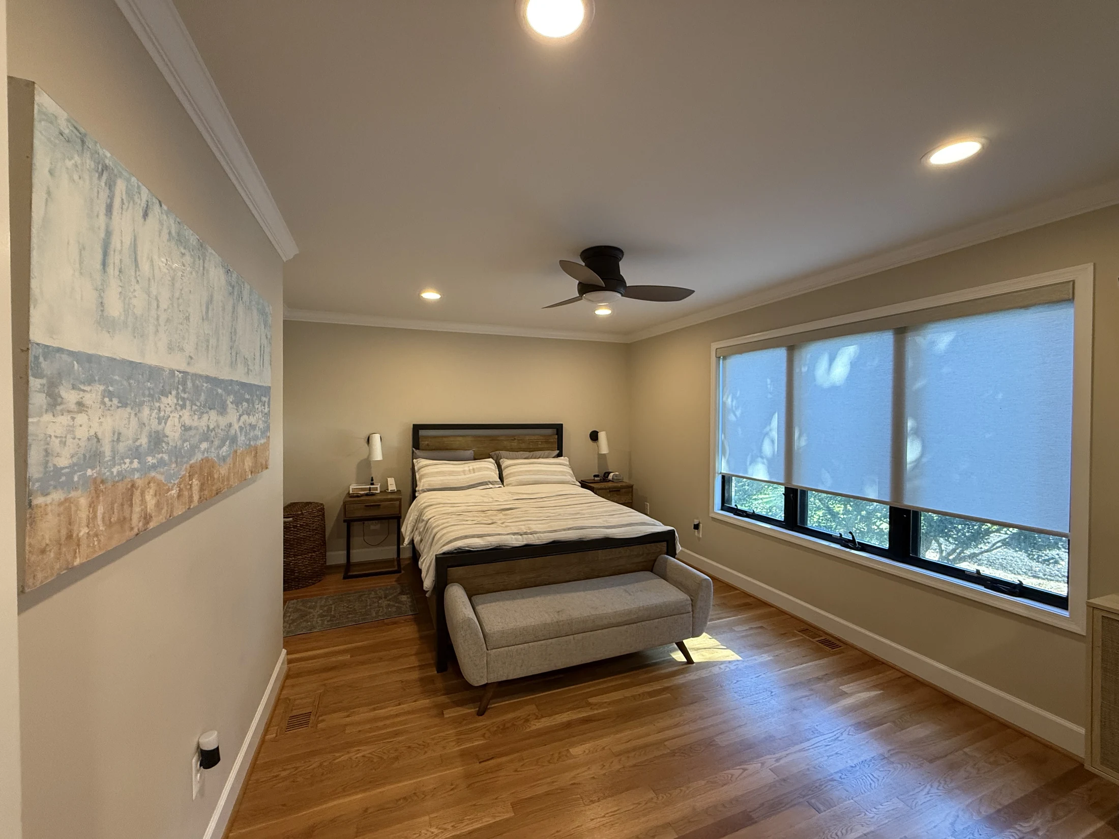Remodeled bedroom with a broad window and hardwood floor