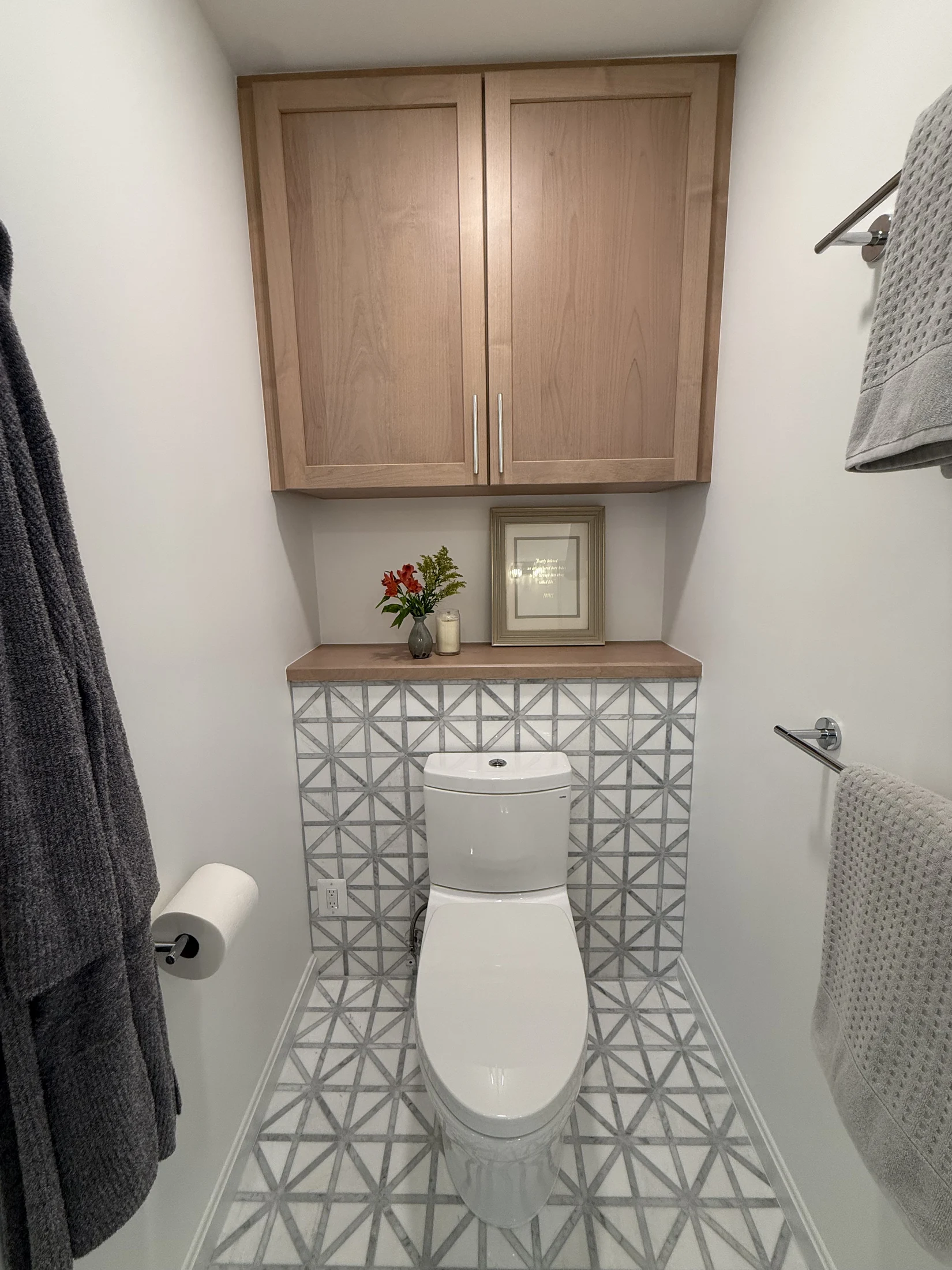 Separate toilet area with patterned tile and overhead cabinetry