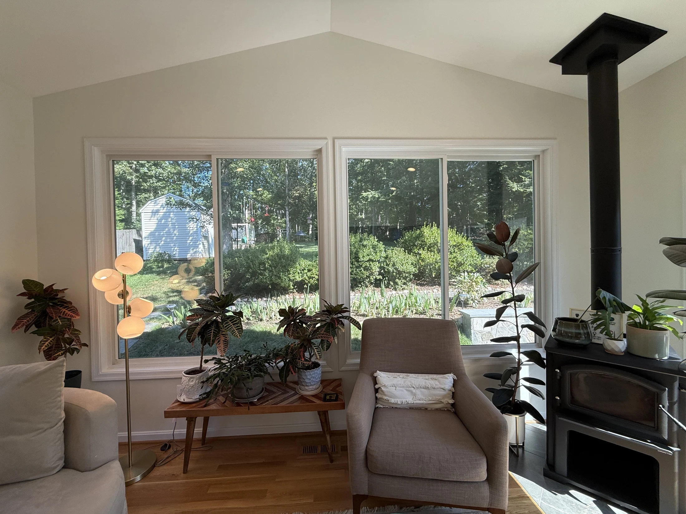 Wood-burning stove and reading chair beside garden-facing windows